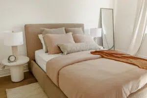 The most welcoming guest bedroom for Airbnb: A taupe upholstered bed with blush pink beddings