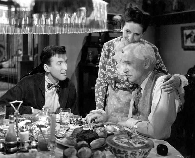 George Bailey sits with his parents at a dining table, where a beaded pendant lamp hangs.