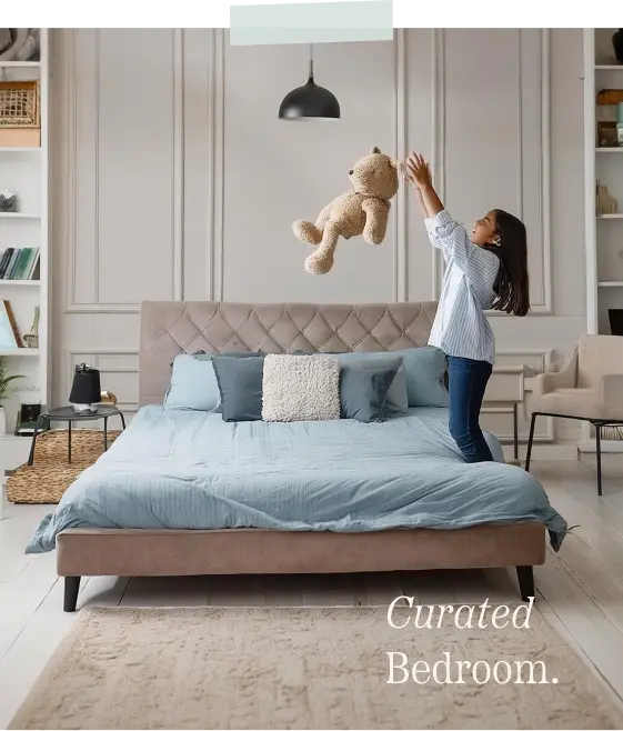 Girl throwing her teddy bear in the air while inside her bedroom