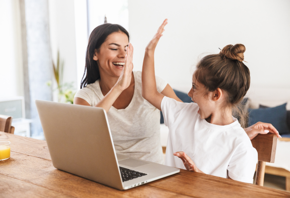 a mother and her daughter giving each other high fives in front of their laptop