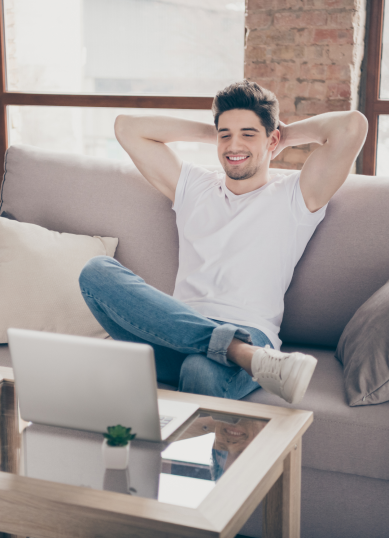 man relaxing on his couch looking at his laptop