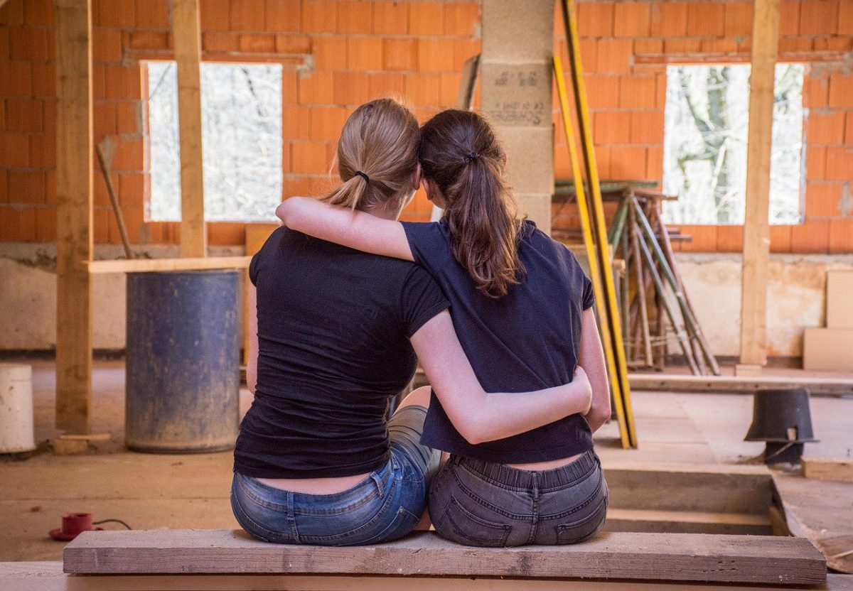 two women hugging in a house under renovation