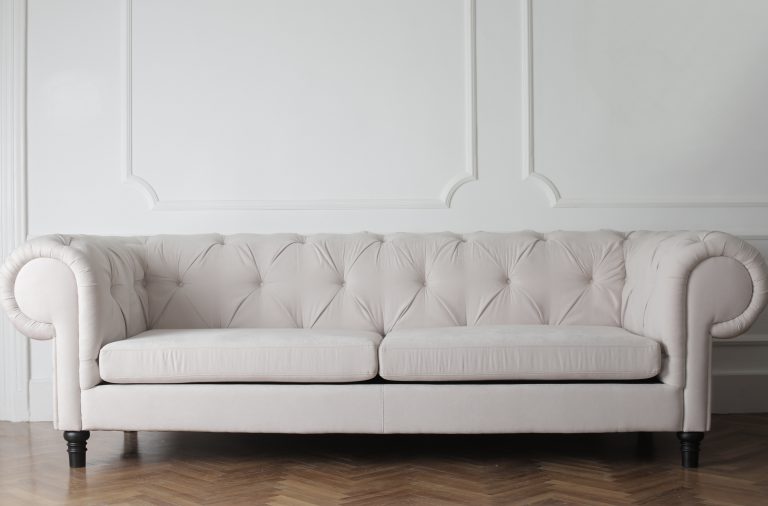 a white couch on wood floor and fancy white wall