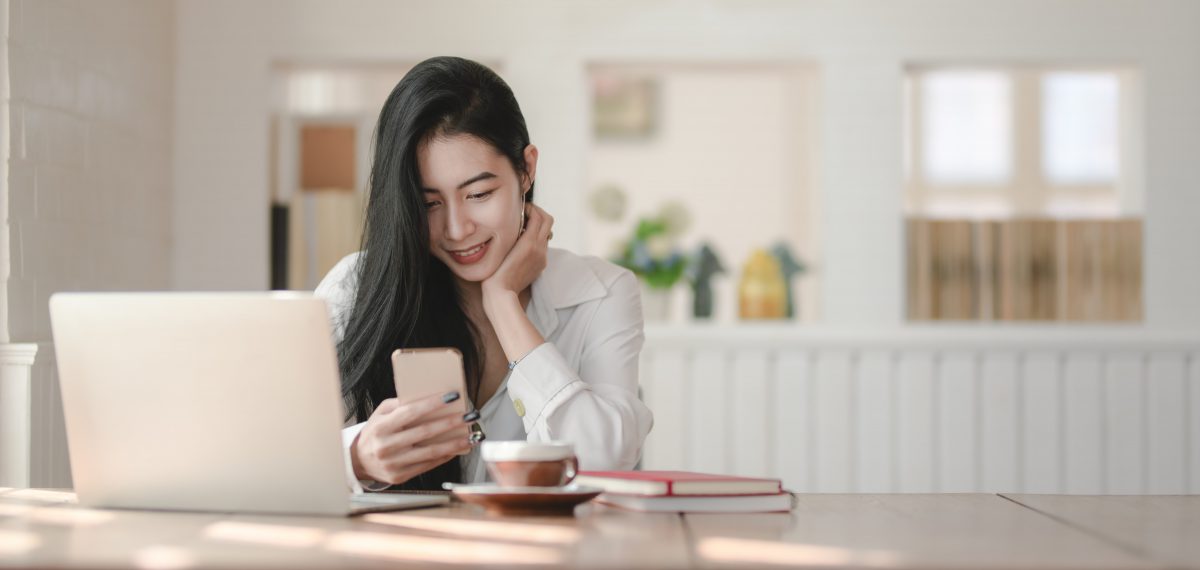 a woman looks down at her phone and smiles